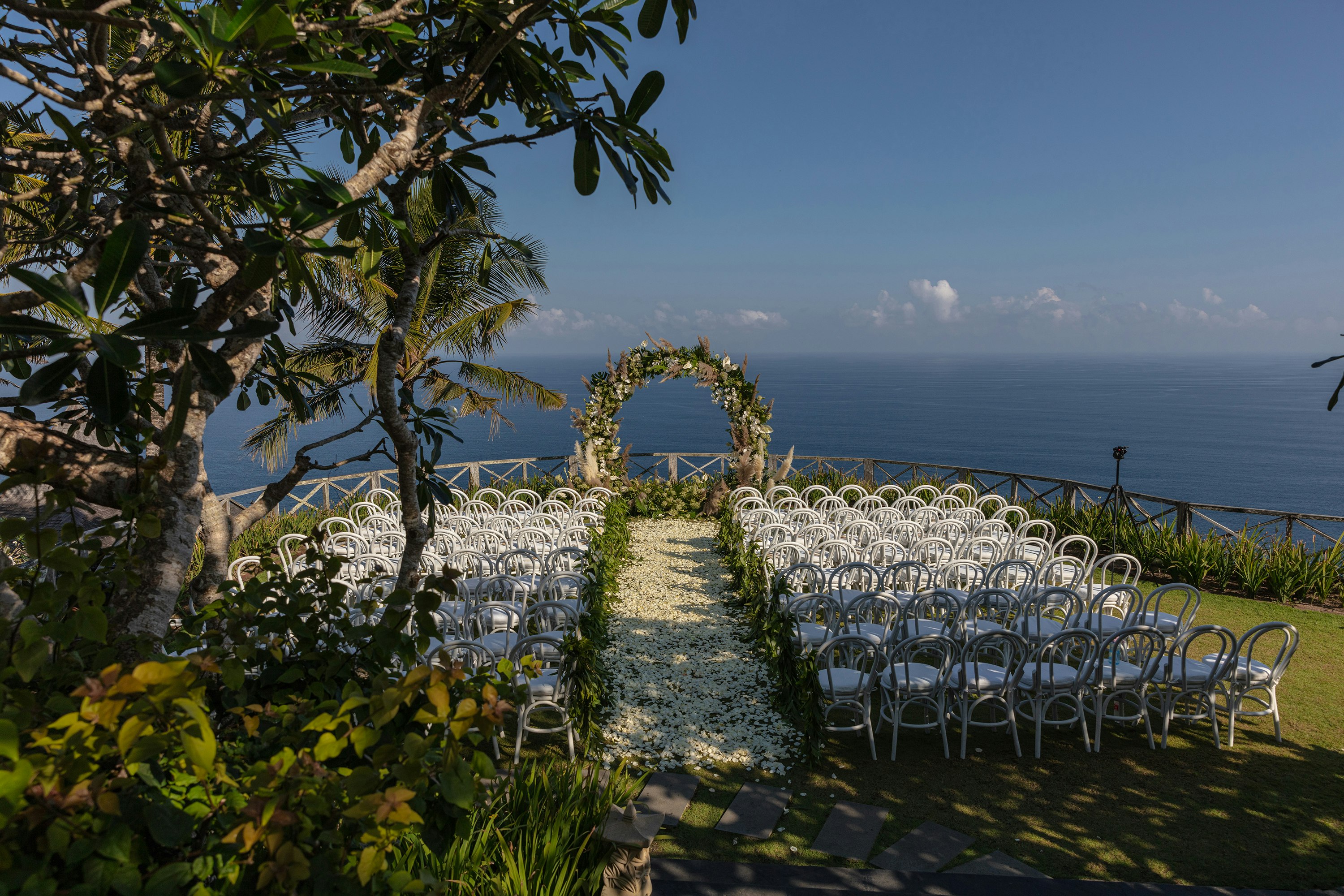 white chairs and green and white floral arch